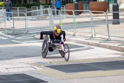 A dedicated athlete competes in a marathon using a racing wheelchair on city streets.